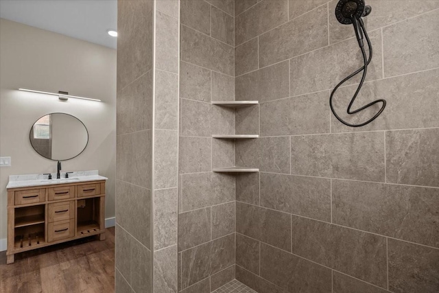 bathroom featuring tiled shower, wood finished floors, and vanity