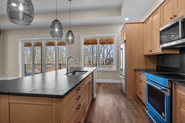 kitchen with decorative light fixtures, sink, a kitchen island with sink, appliances with stainless steel finishes, and dark wood-type flooring