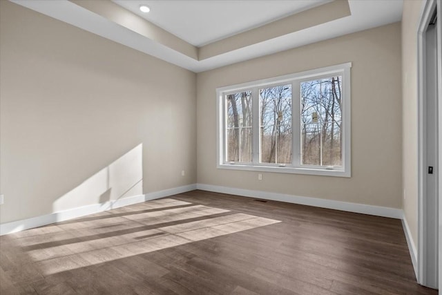 unfurnished room featuring wood-type flooring and a tray ceiling