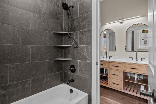 bathroom with double vanity, wood finished floors, a sink, and bathing tub / shower combination