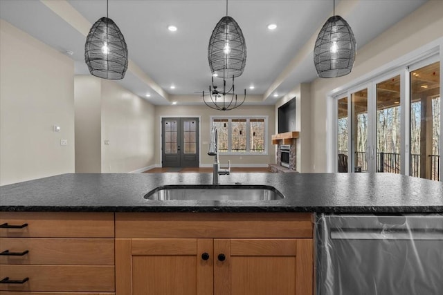 kitchen featuring a raised ceiling, open floor plan, stainless steel dishwasher, a sink, and recessed lighting