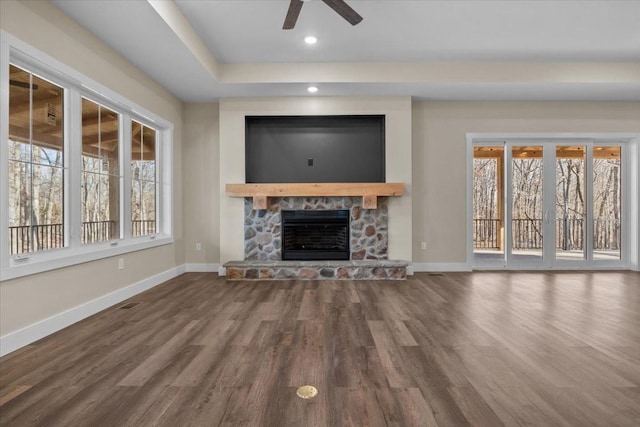 unfurnished living room featuring ceiling fan, hardwood / wood-style flooring, a healthy amount of sunlight, and a fireplace