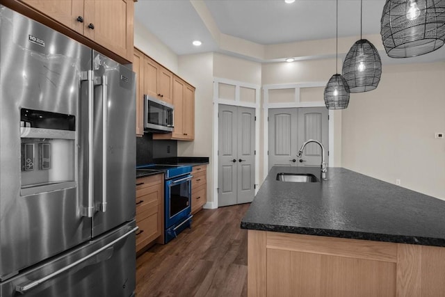 kitchen with dark countertops, light brown cabinetry, appliances with stainless steel finishes, dark wood-type flooring, and a sink