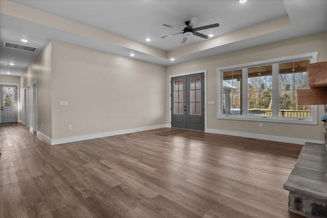 unfurnished living room featuring ceiling fan, french doors, a raised ceiling, and wood-type flooring