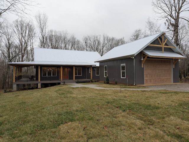 view of front of home featuring covered porch, metal roof, a front yard, and a garage