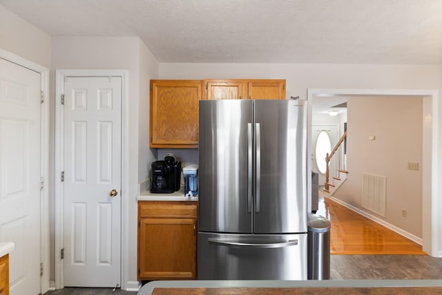 kitchen featuring stainless steel fridge, a textured ceiling, and hardwood / wood-style flooring