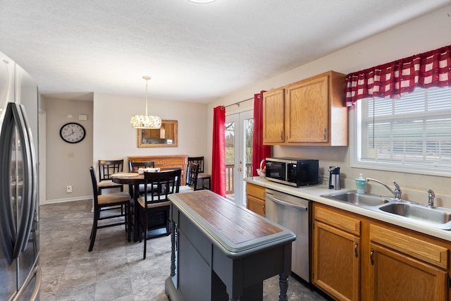 kitchen with pendant lighting, sink, stainless steel appliances, and a chandelier