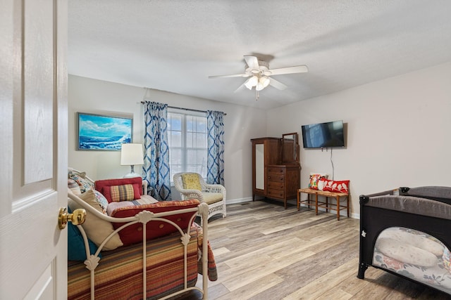 bedroom with ceiling fan, light wood-type flooring, and a textured ceiling