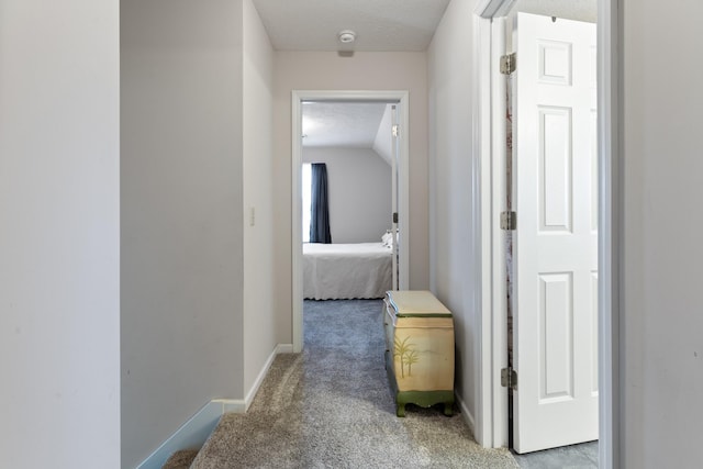 hallway featuring a textured ceiling and light carpet