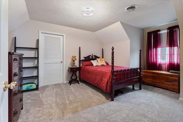 bedroom with a textured ceiling, light colored carpet, and vaulted ceiling