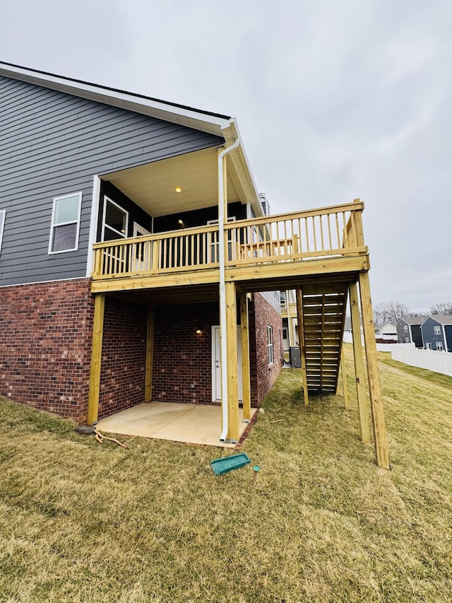 rear view of property featuring a wooden deck, a yard, and a patio area