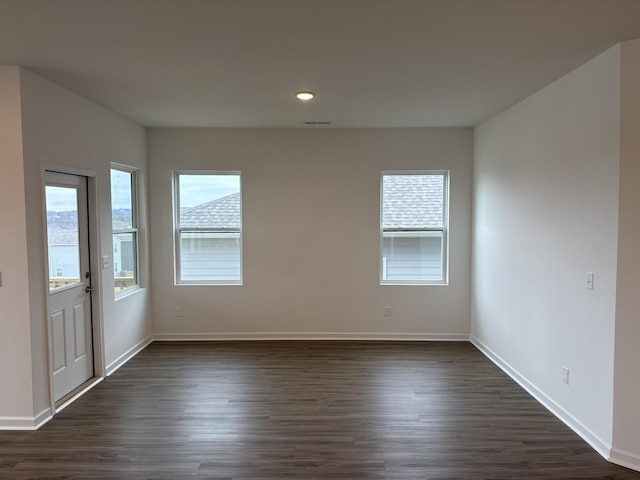 spare room with dark wood-type flooring and a healthy amount of sunlight