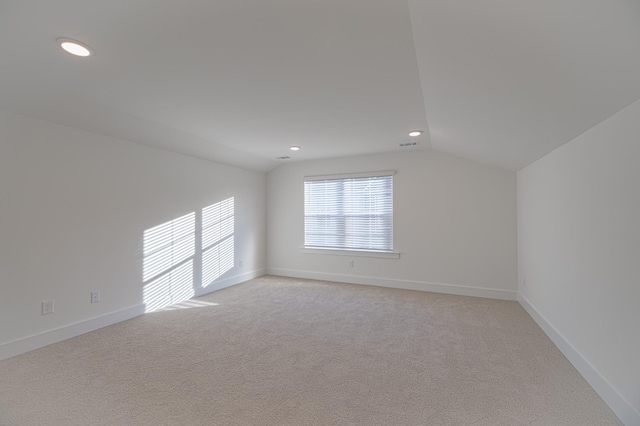 spare room featuring light carpet and vaulted ceiling