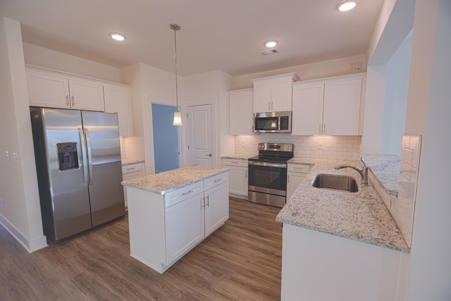 kitchen with pendant lighting, backsplash, sink, white cabinetry, and stainless steel appliances