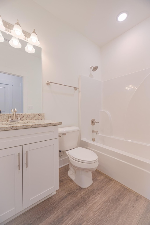 full bathroom featuring washtub / shower combination, vanity, hardwood / wood-style flooring, and toilet