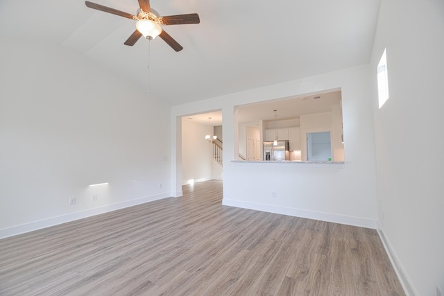 unfurnished living room featuring ceiling fan with notable chandelier, high vaulted ceiling, and light hardwood / wood-style flooring