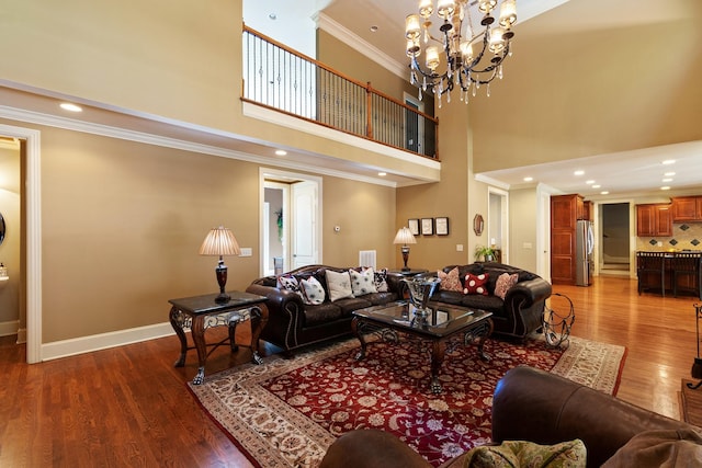 living room featuring hardwood / wood-style floors, an inviting chandelier, ornamental molding, and a high ceiling