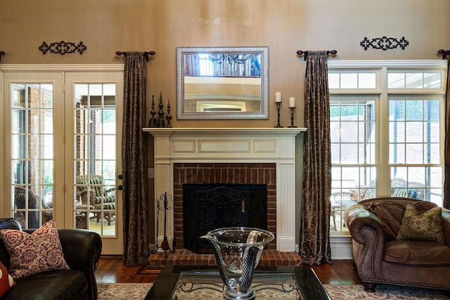 living area with a healthy amount of sunlight, a brick fireplace, and dark wood-type flooring