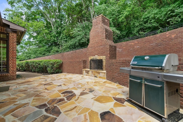 view of patio featuring an outdoor stone fireplace and grilling area