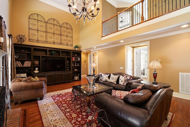 living room featuring a high ceiling, ornamental molding, dark wood-type flooring, and a notable chandelier