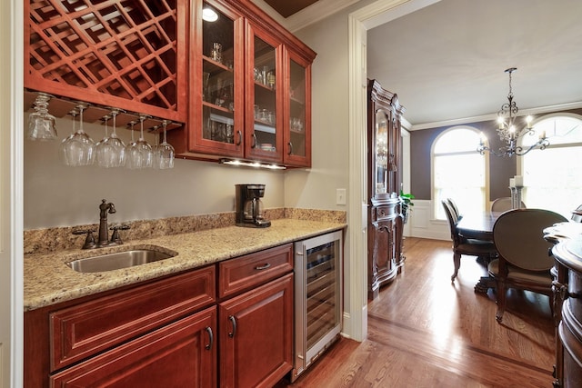 kitchen featuring light stone countertops, light wood-type flooring, ornamental molding, beverage cooler, and sink