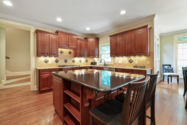 kitchen with dishwasher, crown molding, a kitchen island, wood-type flooring, and a breakfast bar area