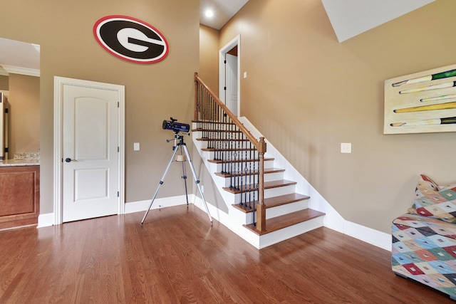 staircase with ornamental molding and hardwood / wood-style flooring