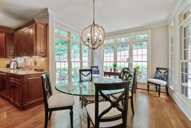 dining space featuring an inviting chandelier, sink, hardwood / wood-style flooring, ornamental molding, and a healthy amount of sunlight