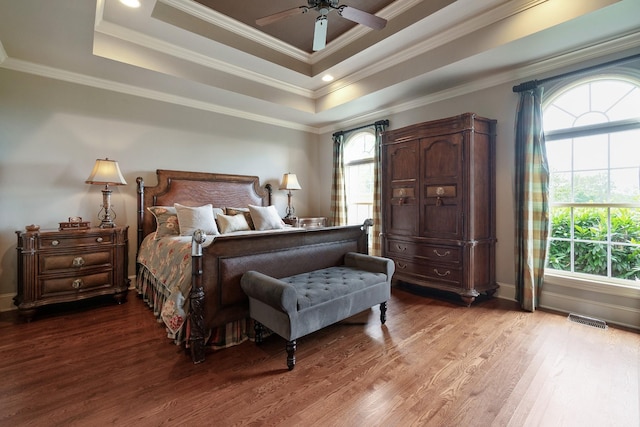 bedroom featuring hardwood / wood-style flooring, ceiling fan, ornamental molding, and a tray ceiling