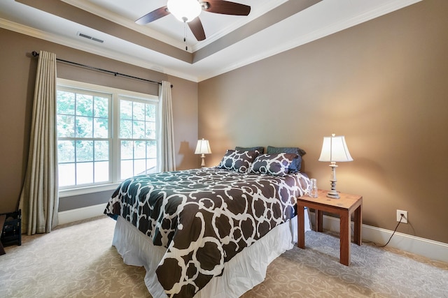 bedroom featuring a tray ceiling, multiple windows, ceiling fan, and ornamental molding