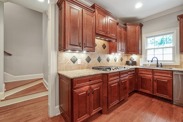 kitchen featuring backsplash, light stone counters, stainless steel appliances, sink, and hardwood / wood-style floors