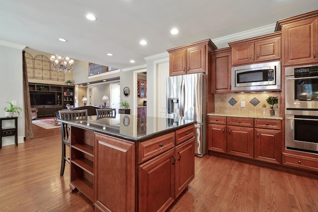 kitchen featuring decorative backsplash, appliances with stainless steel finishes, ornamental molding, an inviting chandelier, and a kitchen island