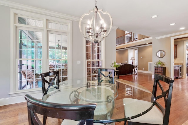 dining area with a notable chandelier, ornamental molding, and light hardwood / wood-style flooring