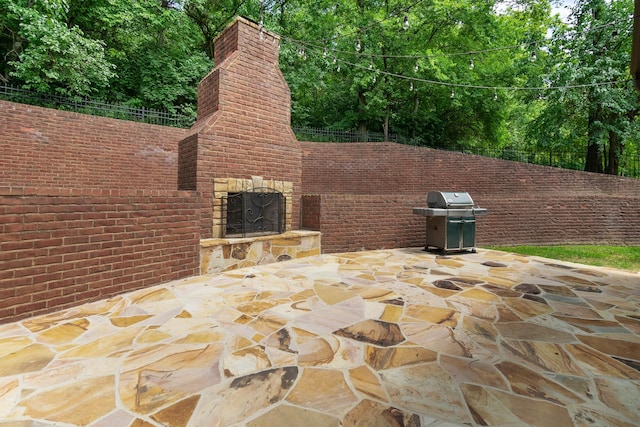 view of patio with an outdoor stone fireplace and area for grilling