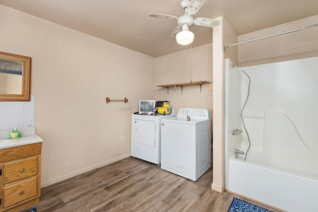 clothes washing area with washing machine and clothes dryer, ceiling fan, and light hardwood / wood-style floors