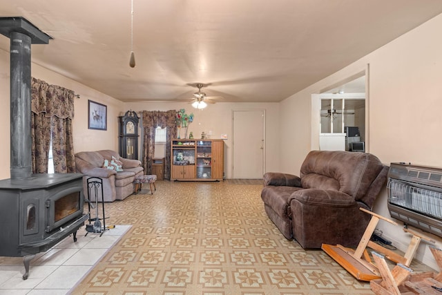 living room featuring a wood stove, ceiling fan, and heating unit