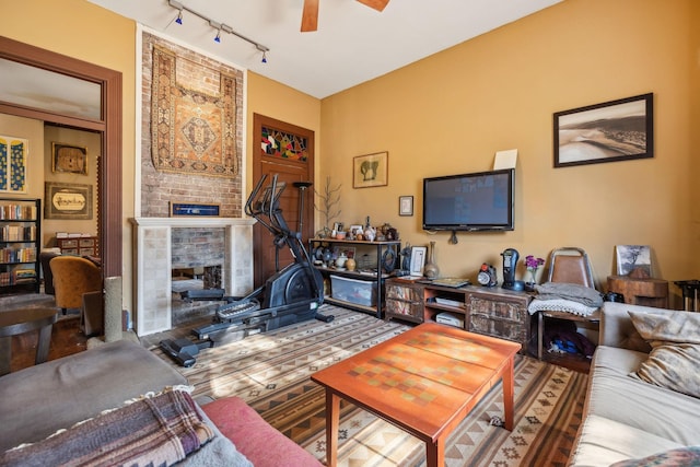 living room with a fireplace, ceiling fan, and rail lighting