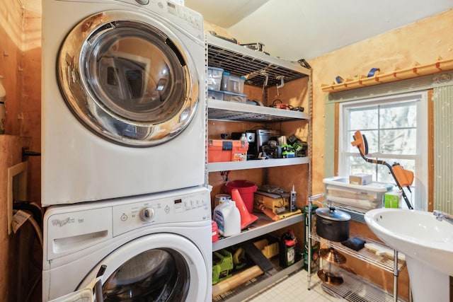 clothes washing area featuring stacked washer / dryer and sink