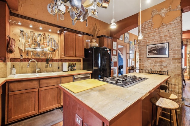 kitchen with tile countertops, sink, a center island, and appliances with stainless steel finishes