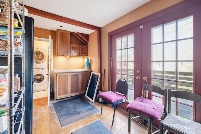 interior space featuring beam ceiling, french doors, light hardwood / wood-style floors, and stacked washer and clothes dryer