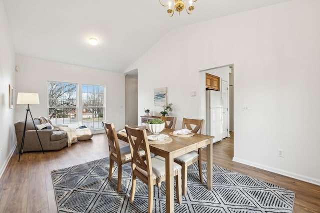 dining area with an inviting chandelier, wood-type flooring, and vaulted ceiling