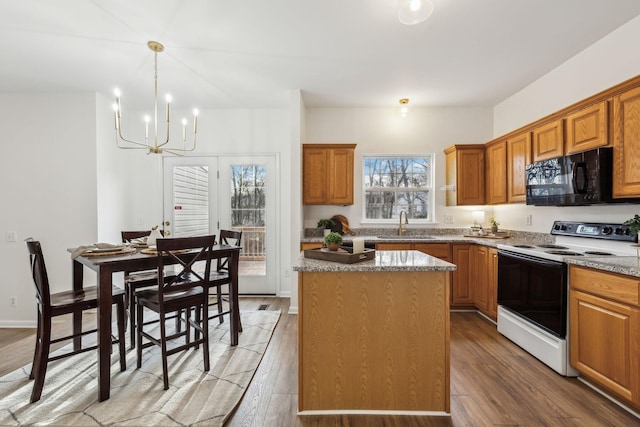 kitchen with electric range, a center island, a notable chandelier, and hardwood / wood-style flooring