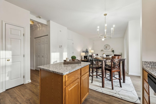 kitchen featuring light stone countertops, pendant lighting, dark hardwood / wood-style flooring, and dishwasher