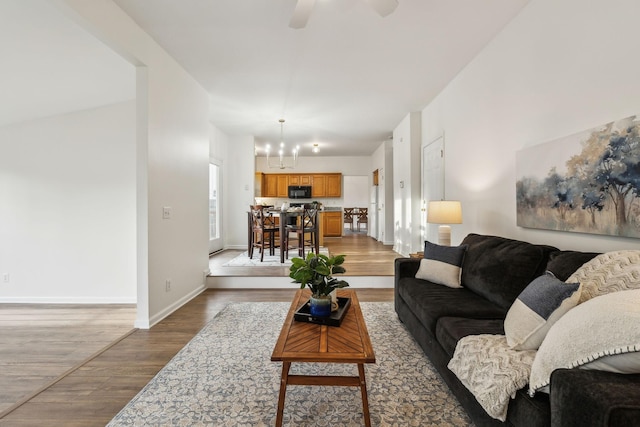 living room with wood-type flooring and ceiling fan with notable chandelier