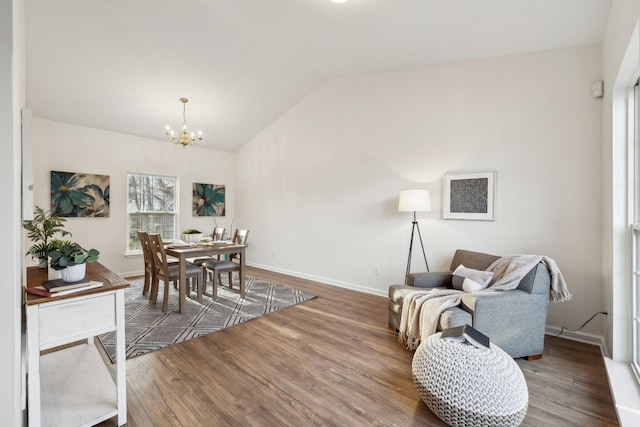 dining area with lofted ceiling, dark hardwood / wood-style floors, and an inviting chandelier