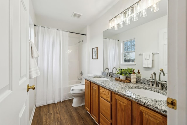 full bathroom with hardwood / wood-style floors, vanity, shower / bath combo, and toilet