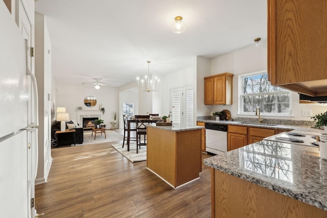 kitchen featuring a center island, white appliances, ceiling fan with notable chandelier, sink, and wood-type flooring