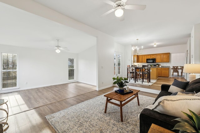 living room with light hardwood / wood-style floors and ceiling fan with notable chandelier