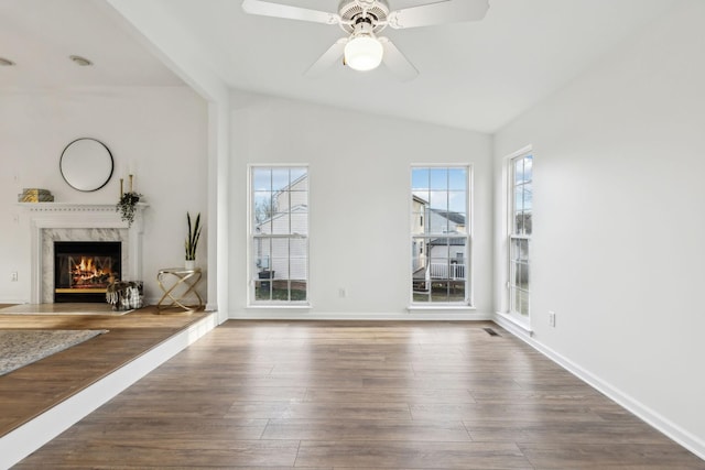 unfurnished living room featuring lofted ceiling, a high end fireplace, dark hardwood / wood-style floors, and ceiling fan