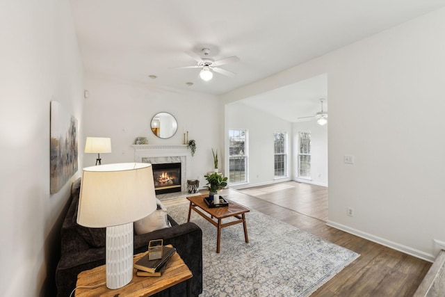 living room featuring ceiling fan, a premium fireplace, dark wood-type flooring, and vaulted ceiling